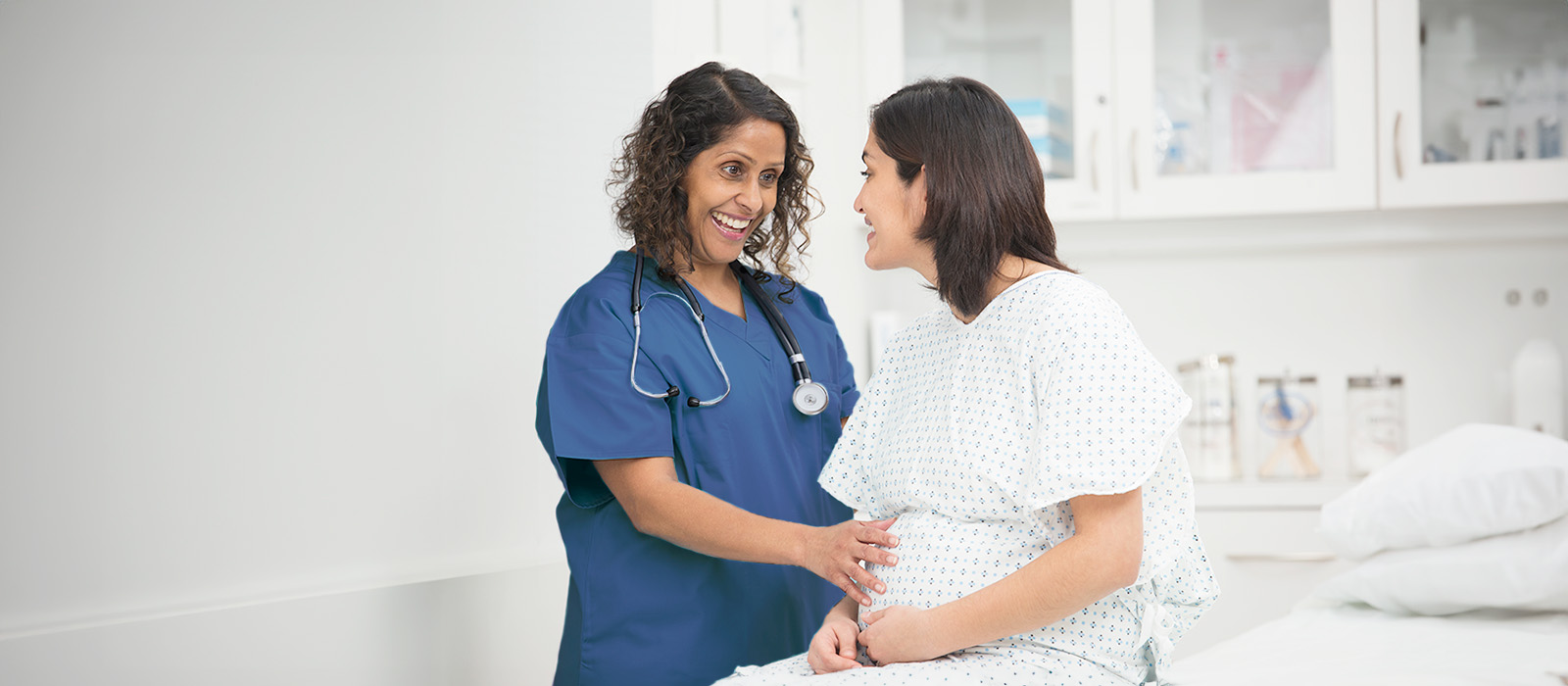 healthcare worker greeting female patient in exam room