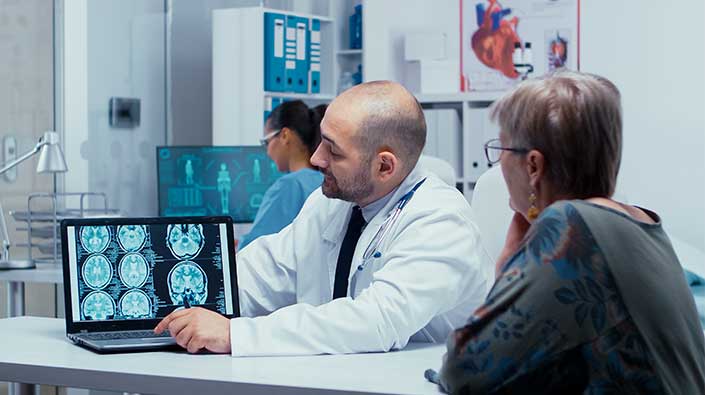 Doctor and patient reviewing scan on laptop