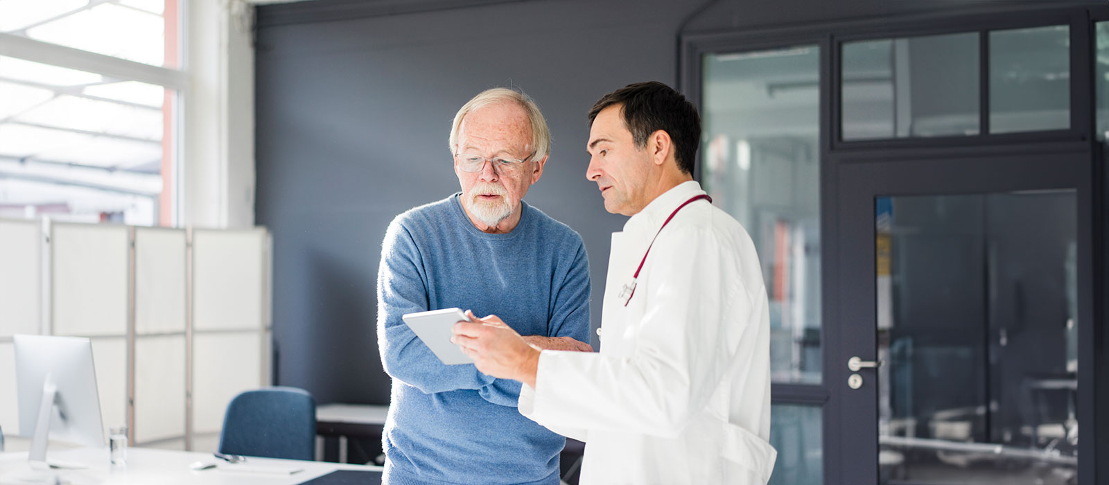 Senior patient viewing tablet with doctor