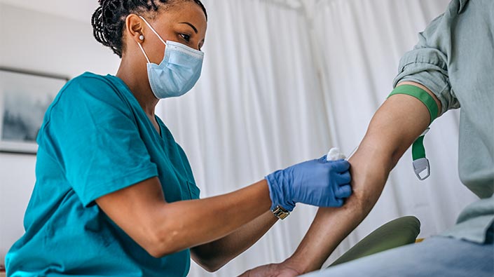 Clinical worker drawing blood from patient