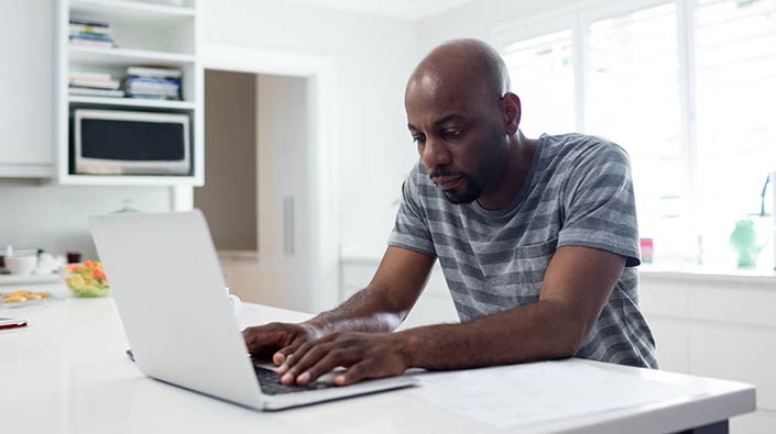 Man typing on his laptop at home