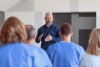 a man wearing professional clothing speaking in front of a room of medical staff